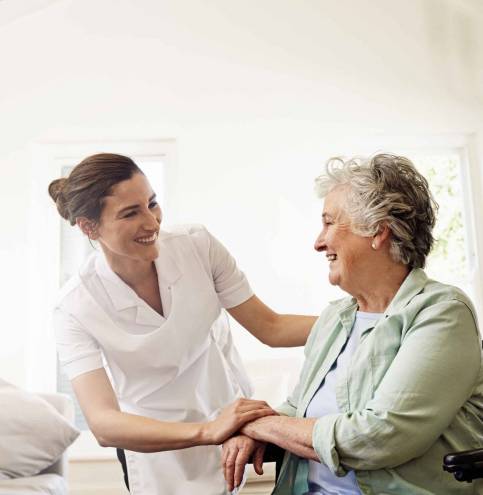 Shot of a smiling caregiver helping a senior woman in a wheelchair at home.